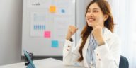 businesswoman in office raising arms to celebrate