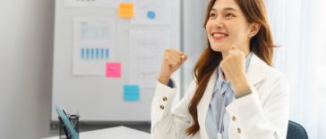 businesswoman in office raising arms to celebrate