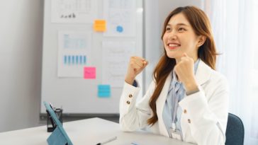 businesswoman in office raising arms to celebrate