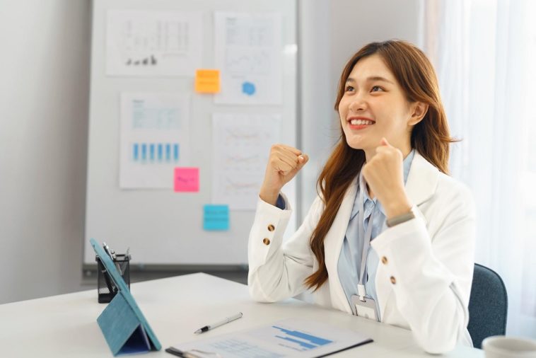 businesswoman in office raising arms to celebrate