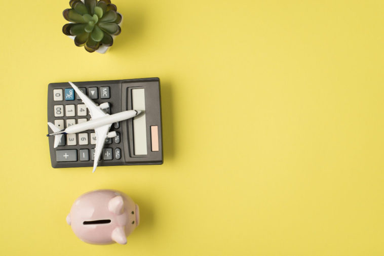 plane model on a calculator next to a piggy bank