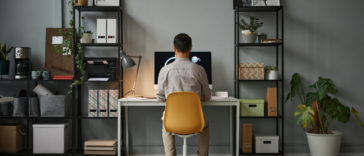 back view of a man using a computer in a home office