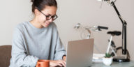 woman sitting at a table typing on a laptop