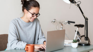 woman sitting at a table typing on a laptop