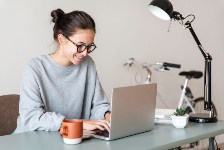 woman sitting at a table typing on a laptop