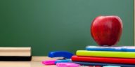 school supplies on a desk in front of a chalkboard