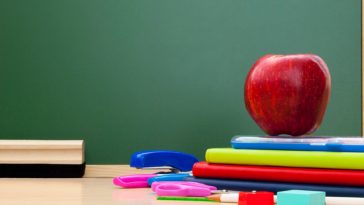 school supplies on a desk in front of a chalkboard