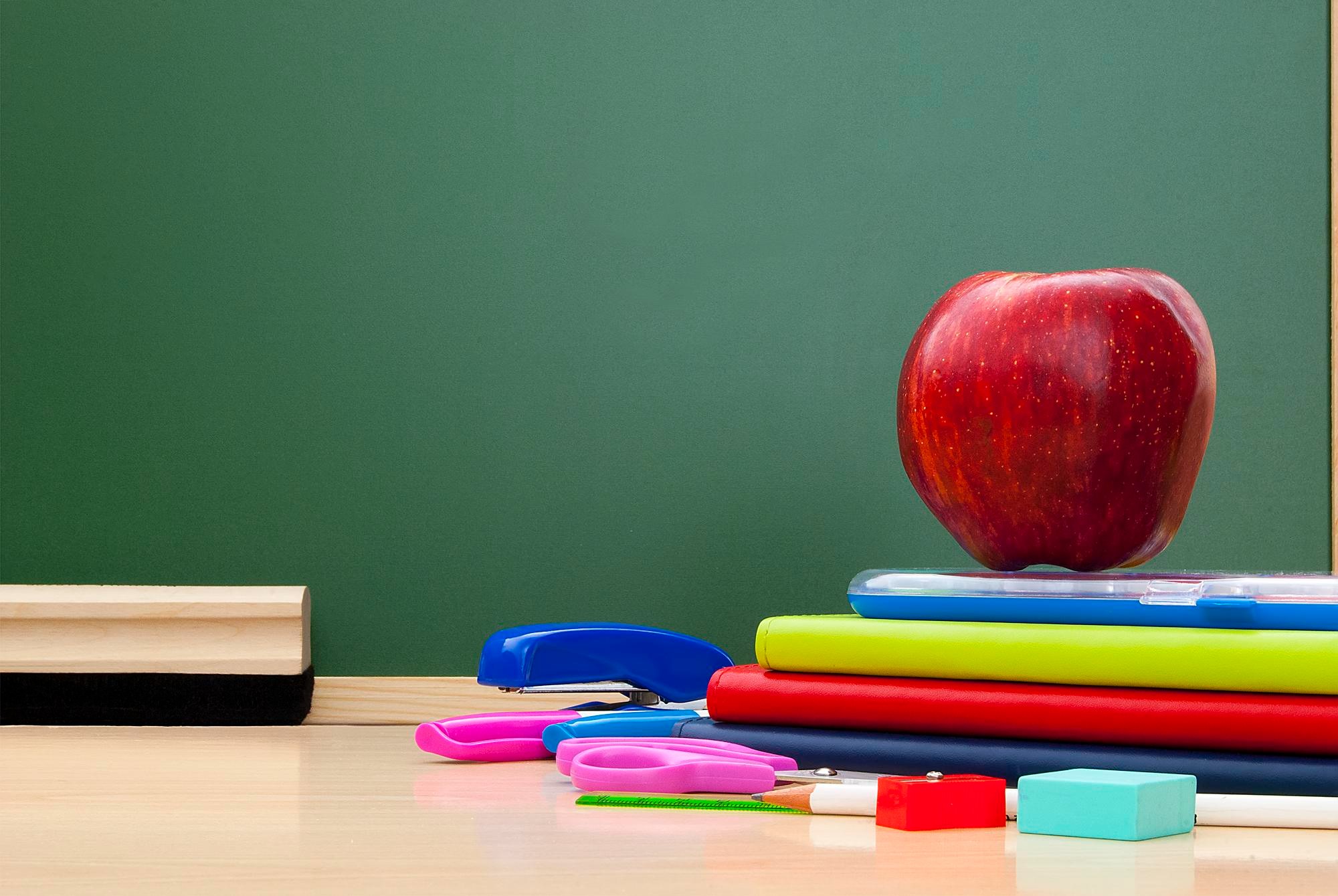 school supplies on a desk in front of a chalkboard