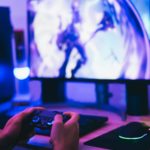 hands holding a joystick in front of a computer screen