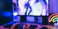 hands holding a joystick in front of a computer screen