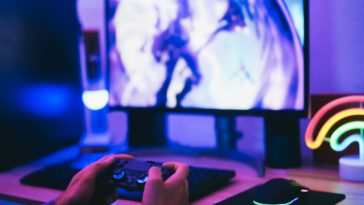 hands holding a joystick in front of a computer screen