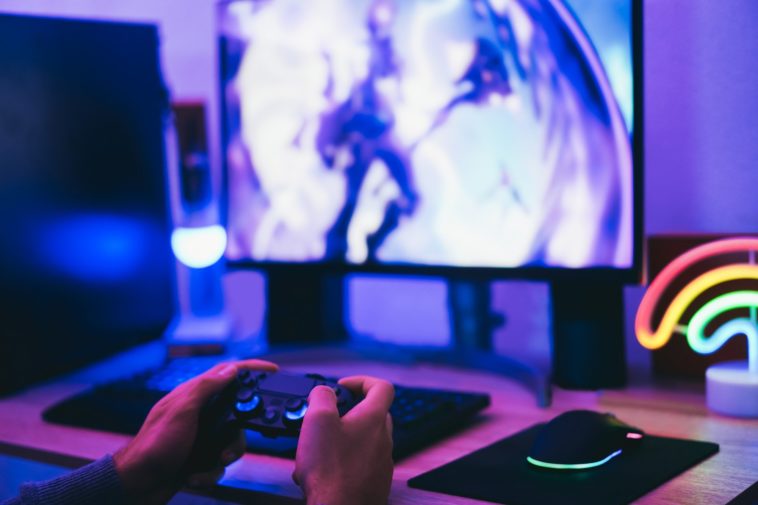 hands holding a joystick in front of a computer screen