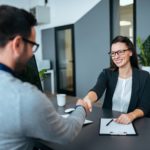 two people in an office shaking hands over a desk