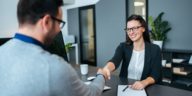 two people in an office shaking hands over a desk