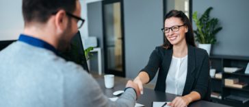 two people in an office shaking hands over a desk