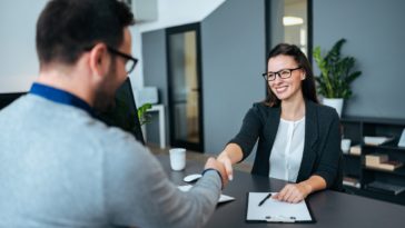two people in an office shaking hands over a desk