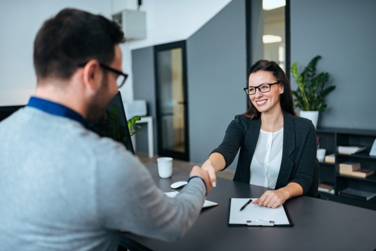 two people in an office shaking hands over a desk