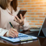 businesswoman with a phone and business report analyzing sales