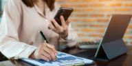 businesswoman with a phone and business report analyzing sales