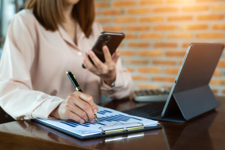 businesswoman with a phone and business report analyzing sales