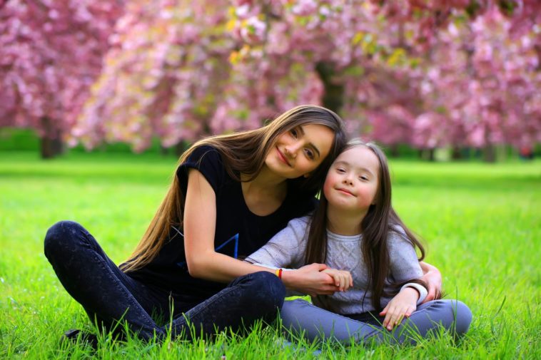 young woman and a little girl sitting on the grass in a park