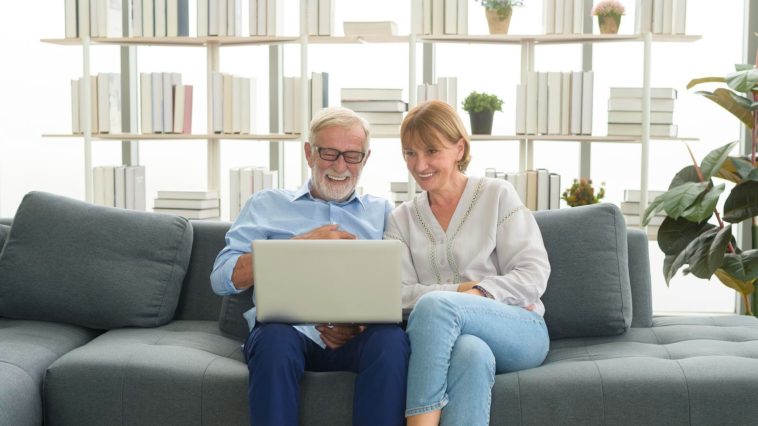 senior couple sitting on a couch using a laptop