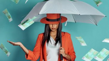 woman holding an umbrella being showered by cash