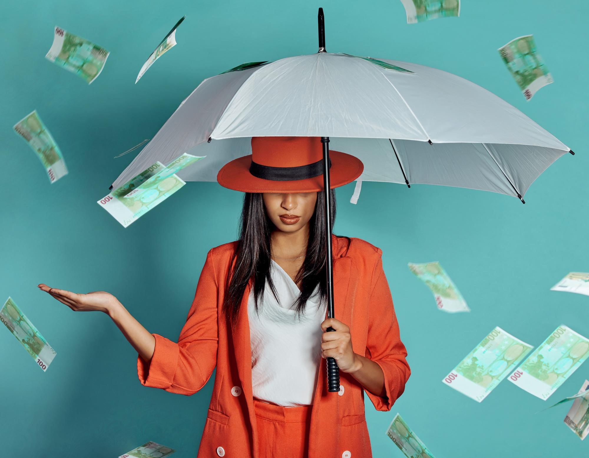 woman holding an umbrella being showered by cash