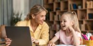 woman and little girl sitting at a desk and using a laptop to learn