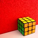 solved Rubik's cube next to a red wall