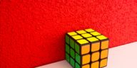 solved Rubik's cube next to a red wall