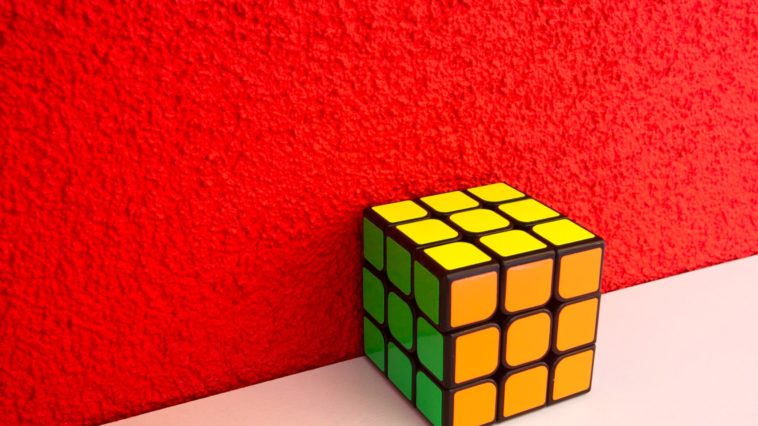 solved Rubik's cube next to a red wall