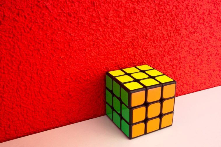 solved Rubik's cube next to a red wall