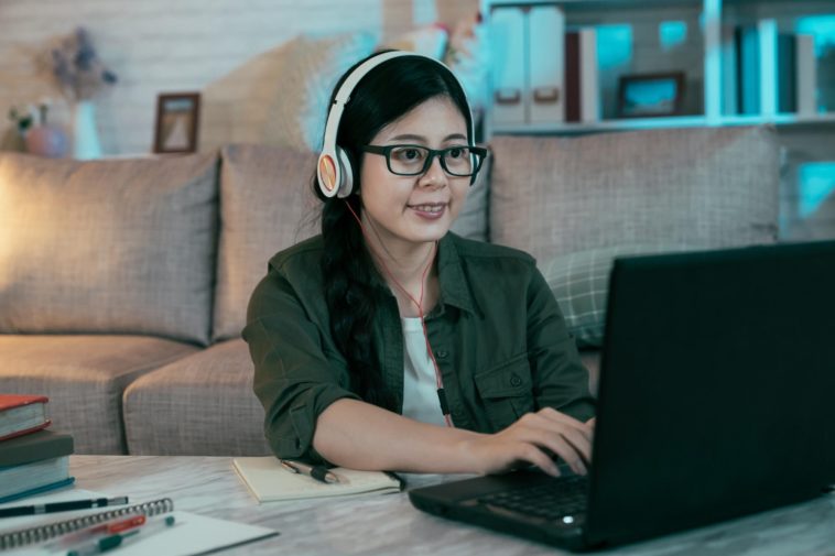 woman with headphones typing on a laptop