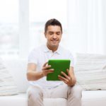 man sitting on a couch using a tablet