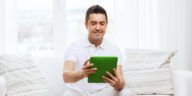 man sitting on a couch using a tablet