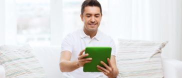 man sitting on a couch using a tablet