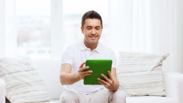 man sitting on a couch using a tablet