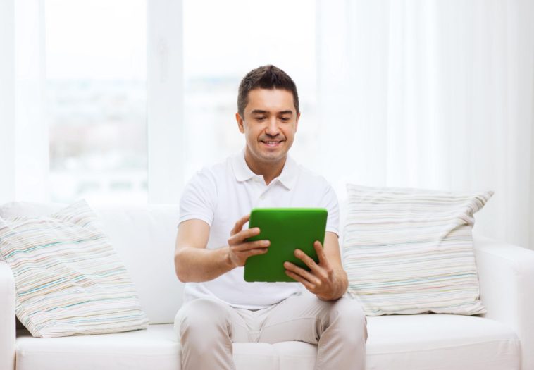 man sitting on a couch using a tablet