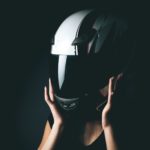 woman putting on a motorcycle helmet