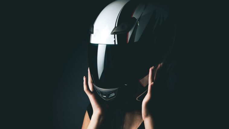 woman putting on a motorcycle helmet