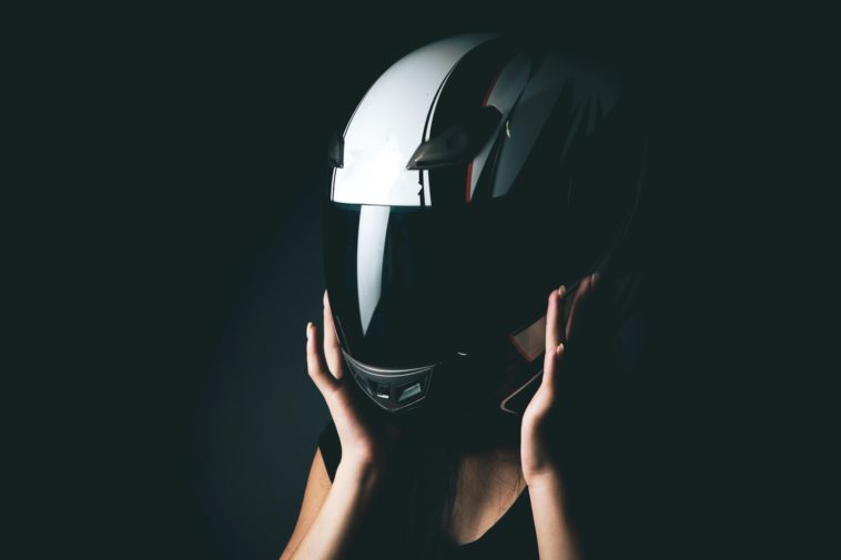 woman putting on a motorcycle helmet