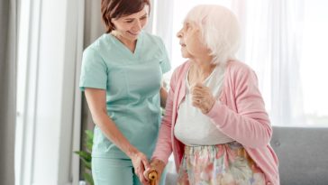 nurse helping an elderly woman walk