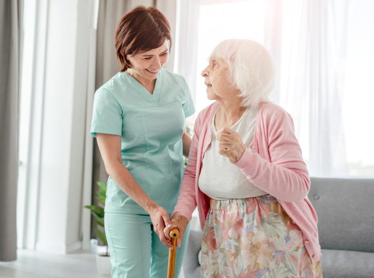 nurse helping an elderly woman walk