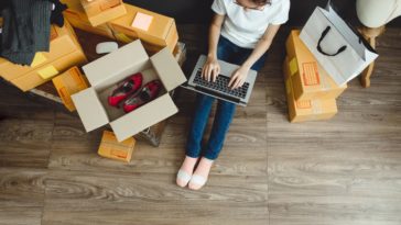 woman with a laptop in her lap surrounded by boxes