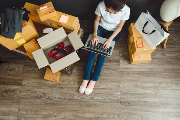 woman with a laptop in her lap surrounded by boxes