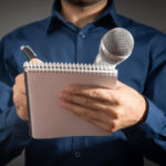 journalist holding microphone notepad and pen