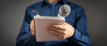 journalist holding microphone notepad and pen