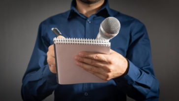 journalist holding microphone notepad and pen