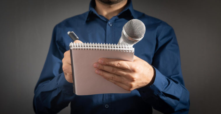 journalist holding microphone notepad and pen